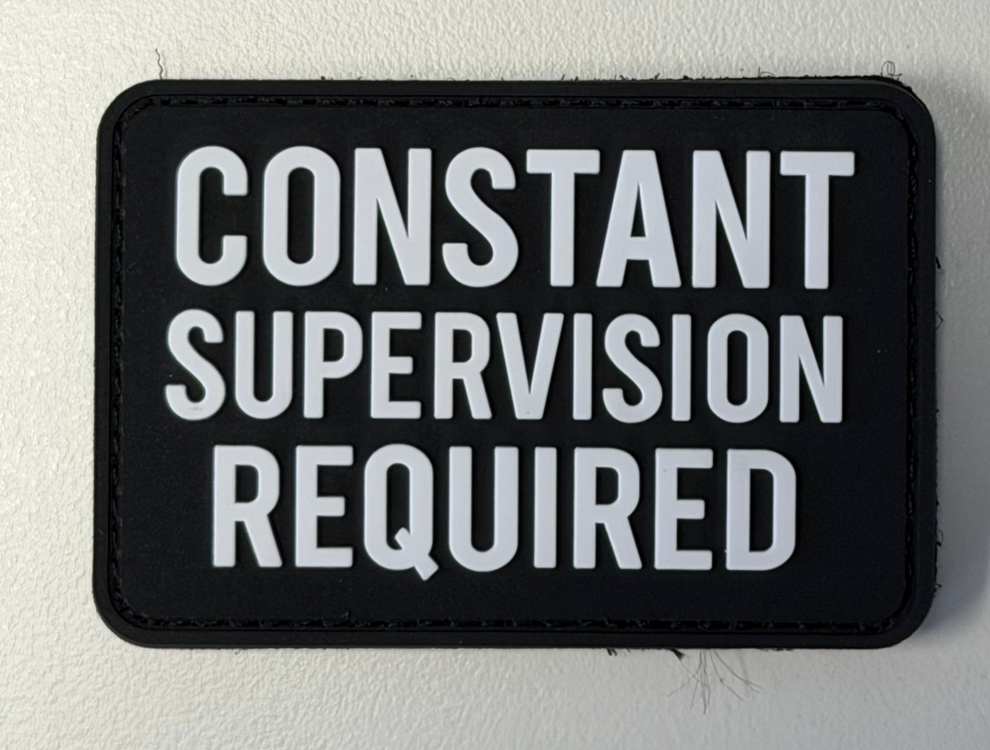 Black patch with white text 'CONSTANT SUPERVISION REQUIRED' on a light gray background