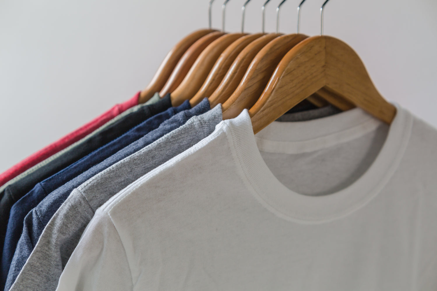 Multi-coloured t shirts on coat hangers. 